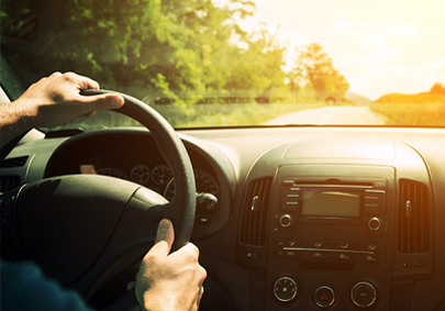 dyk 02 16 18 Man driving a car on a country road in bright sunshine