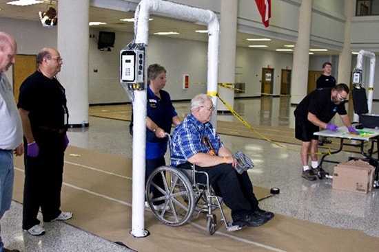An older man in a wheelchair being screened for radiation