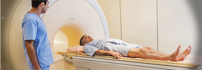A patient lying on the table in front of a computerized tomography machine.