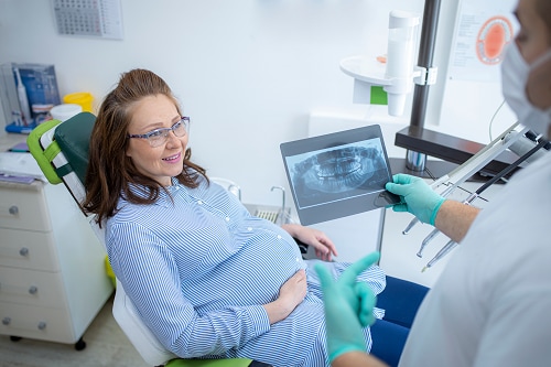 Dentist showing a pregnant patient an x-ray.