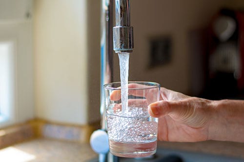 a glass being filled with water from a sink faucet