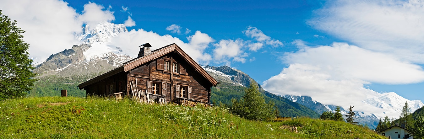 Cabin in a field with mountains in the background