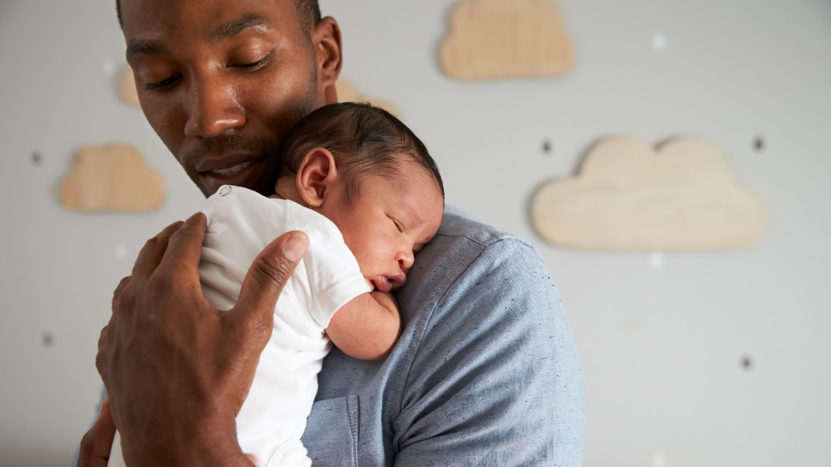 Black young father holding newborn baby on his shoulder
