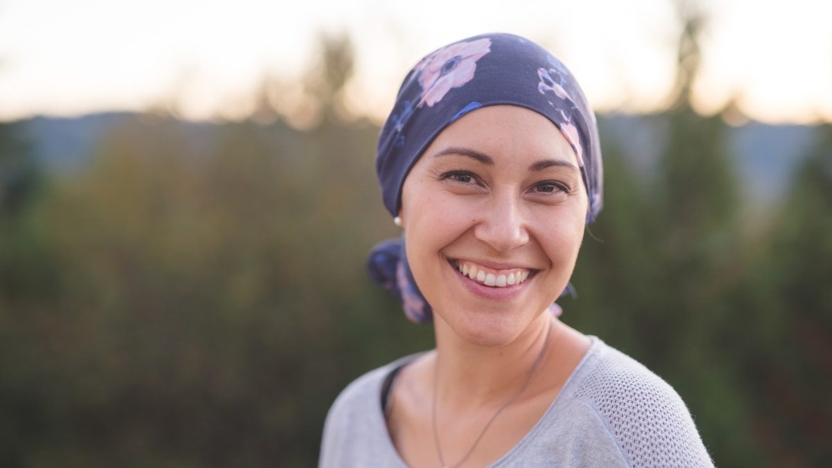 White young woman wearing a purple scarf on her head, concealing hair loss.