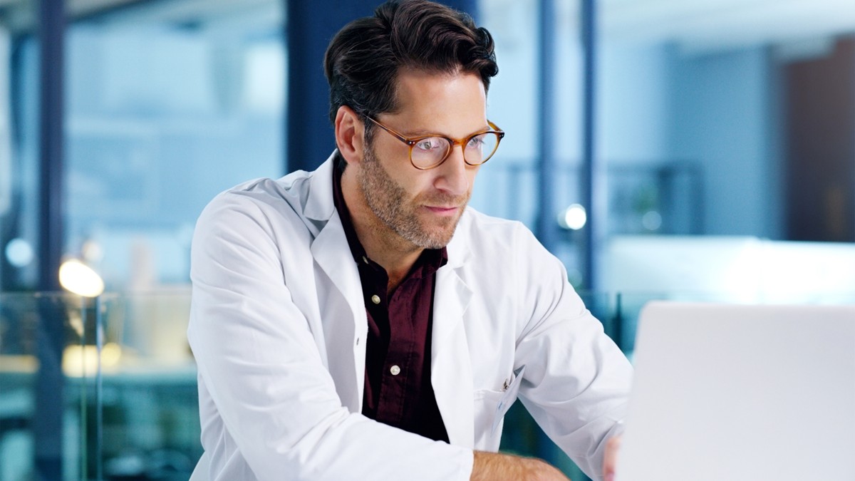 A male healthcare provider takes a virtual training course on his laptop.