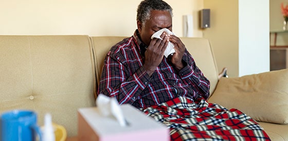 Older man sneezing into a tissue