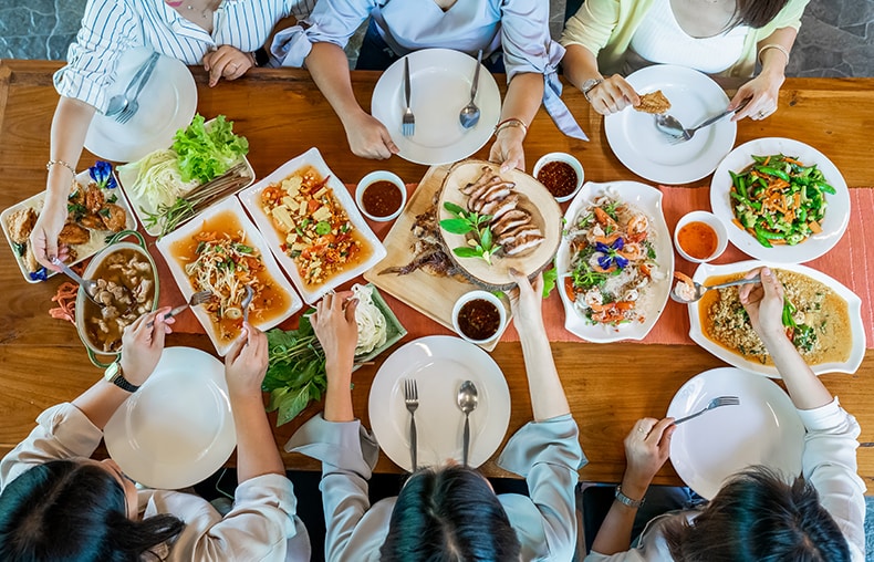 Topview of Thai local food such as Somtum papaya salad, grilled pork, tomyum, vegetable and shrimp curry are arranged table.