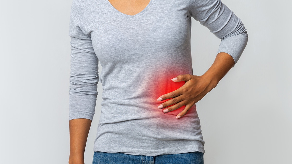 A woman holding the left side of her stomach.