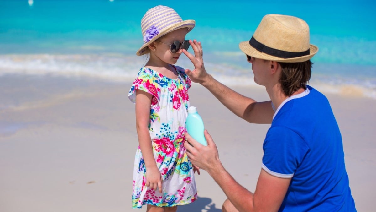 a father putting sunscreen on his young daughter