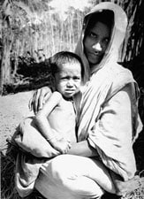 A Bangladeshi woman holds a small child in her arms.