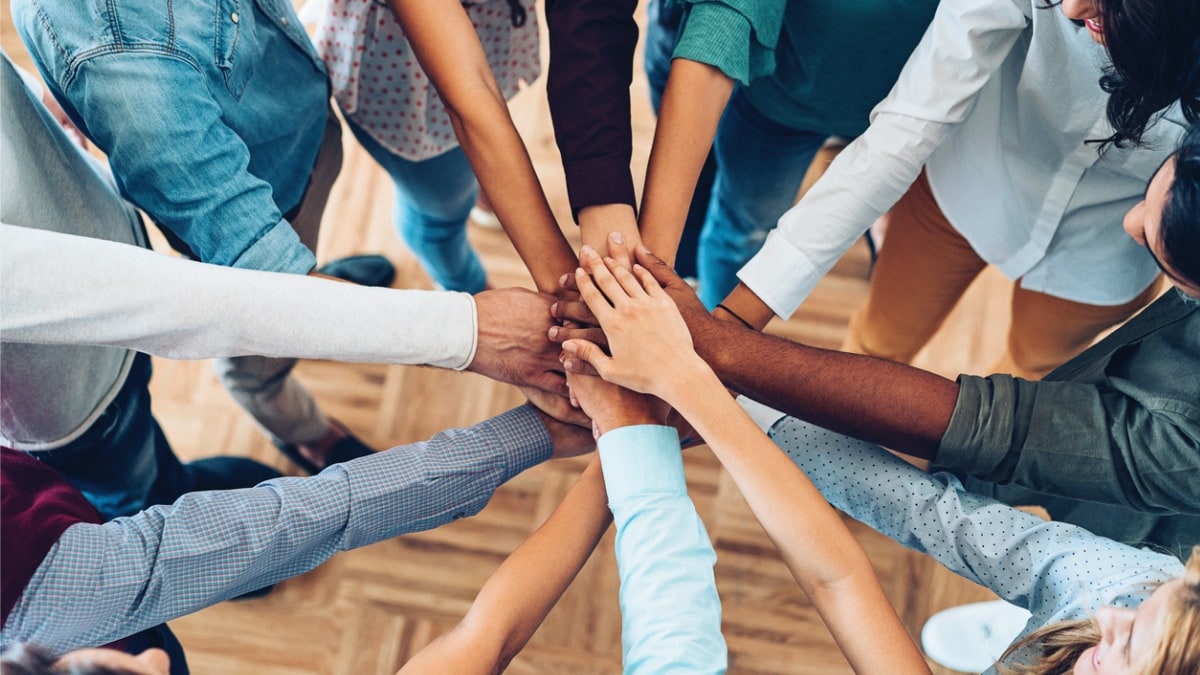 A group of people placing their hands together, symbolizing social connectedness