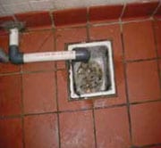 Desagüe del piso tapado con desechos, agua en el piso de la cocina