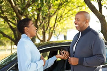 Padre e hijo hablando junto al automóvil con llaves en mano