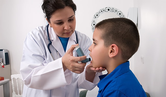 Doctora administrando un inhalador a un niño