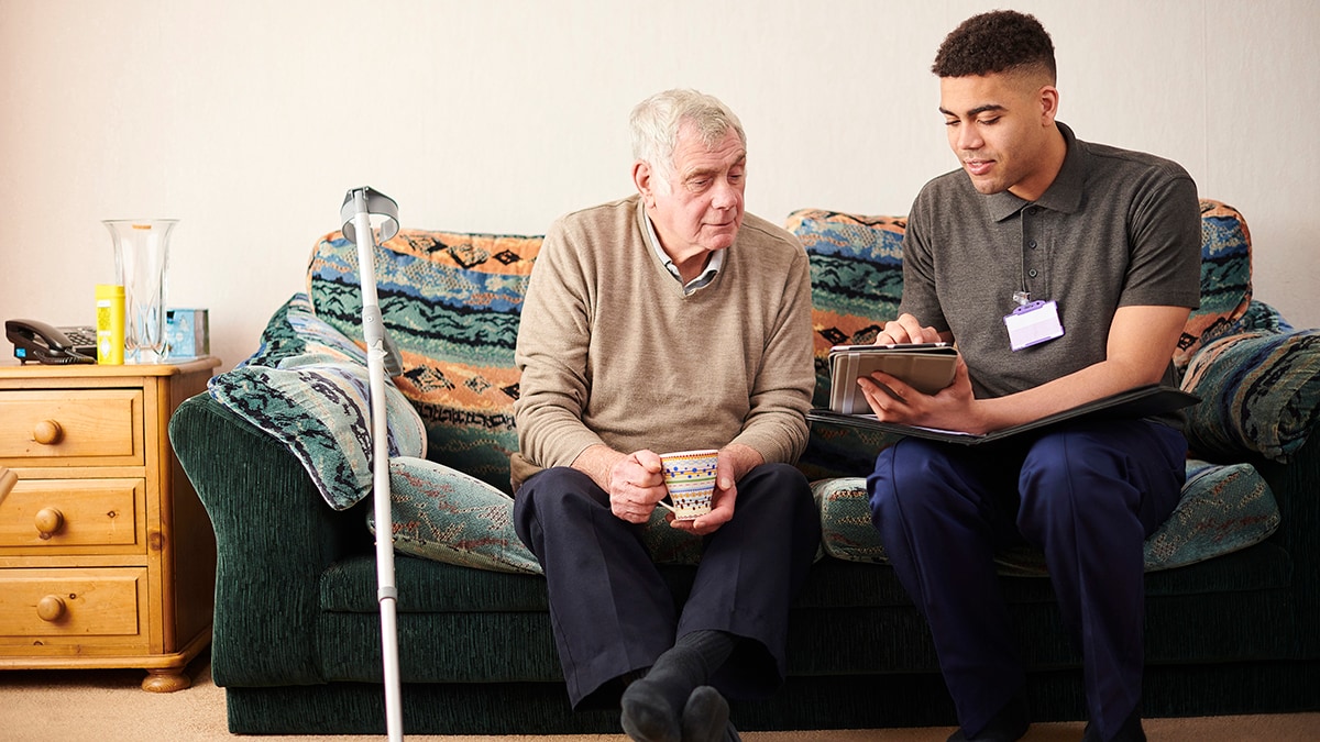 Young man and older man on a couch looking at a clipboard