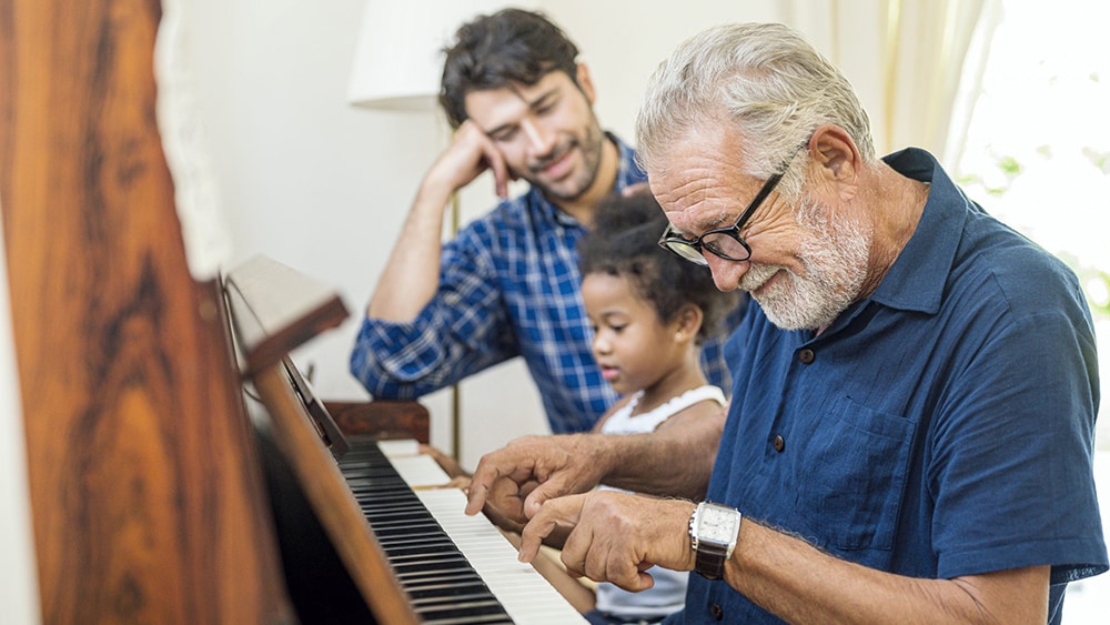 Family spend time happy together with the grandfather playing piano
