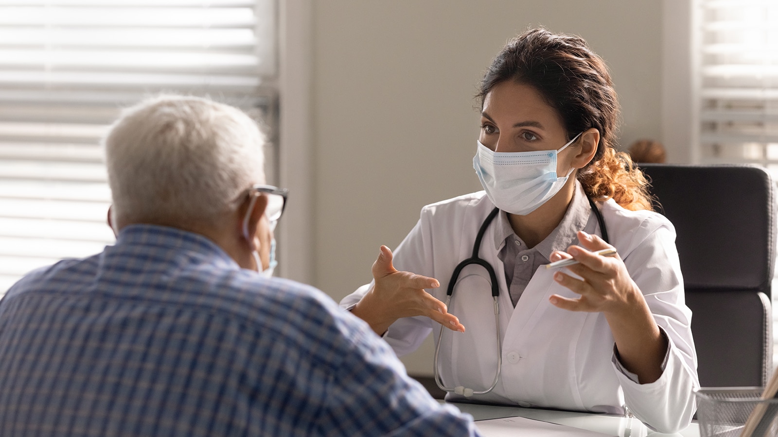 Close up female therapist wearing face mask consulting older patient