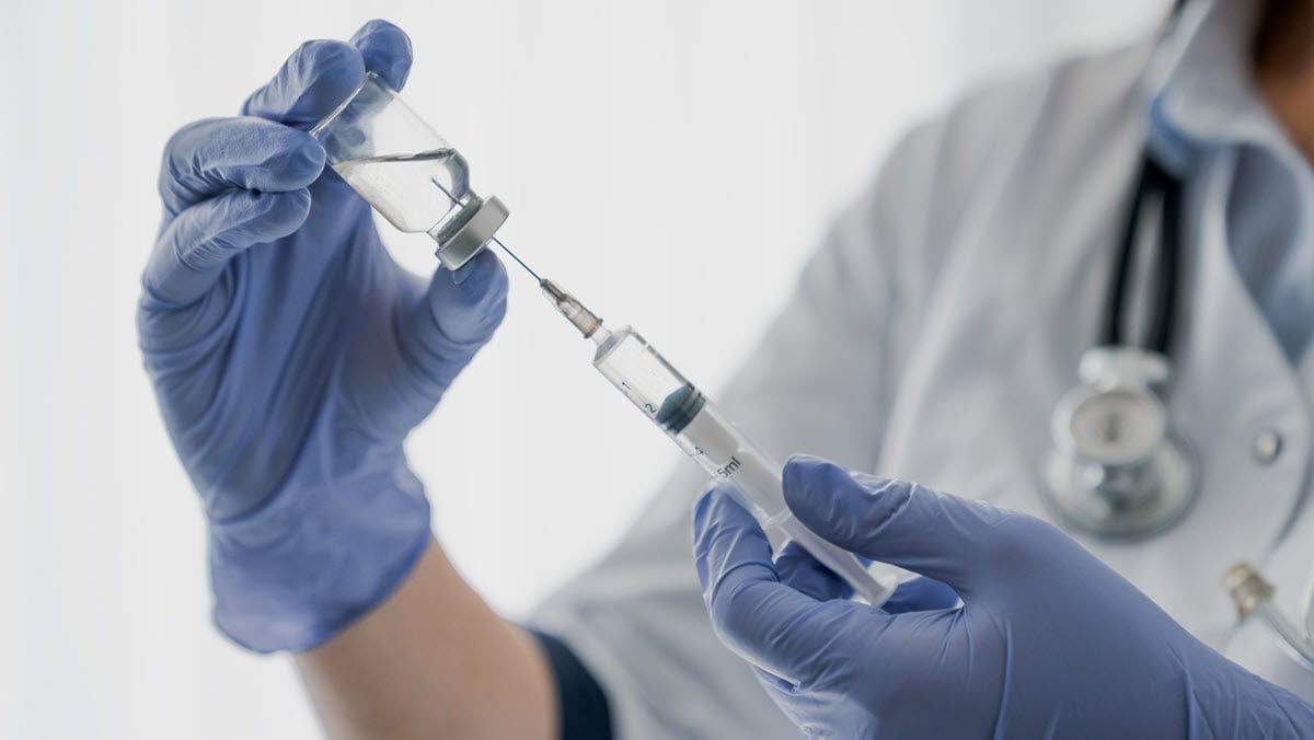 A health care provider prepares a vaccine for administration