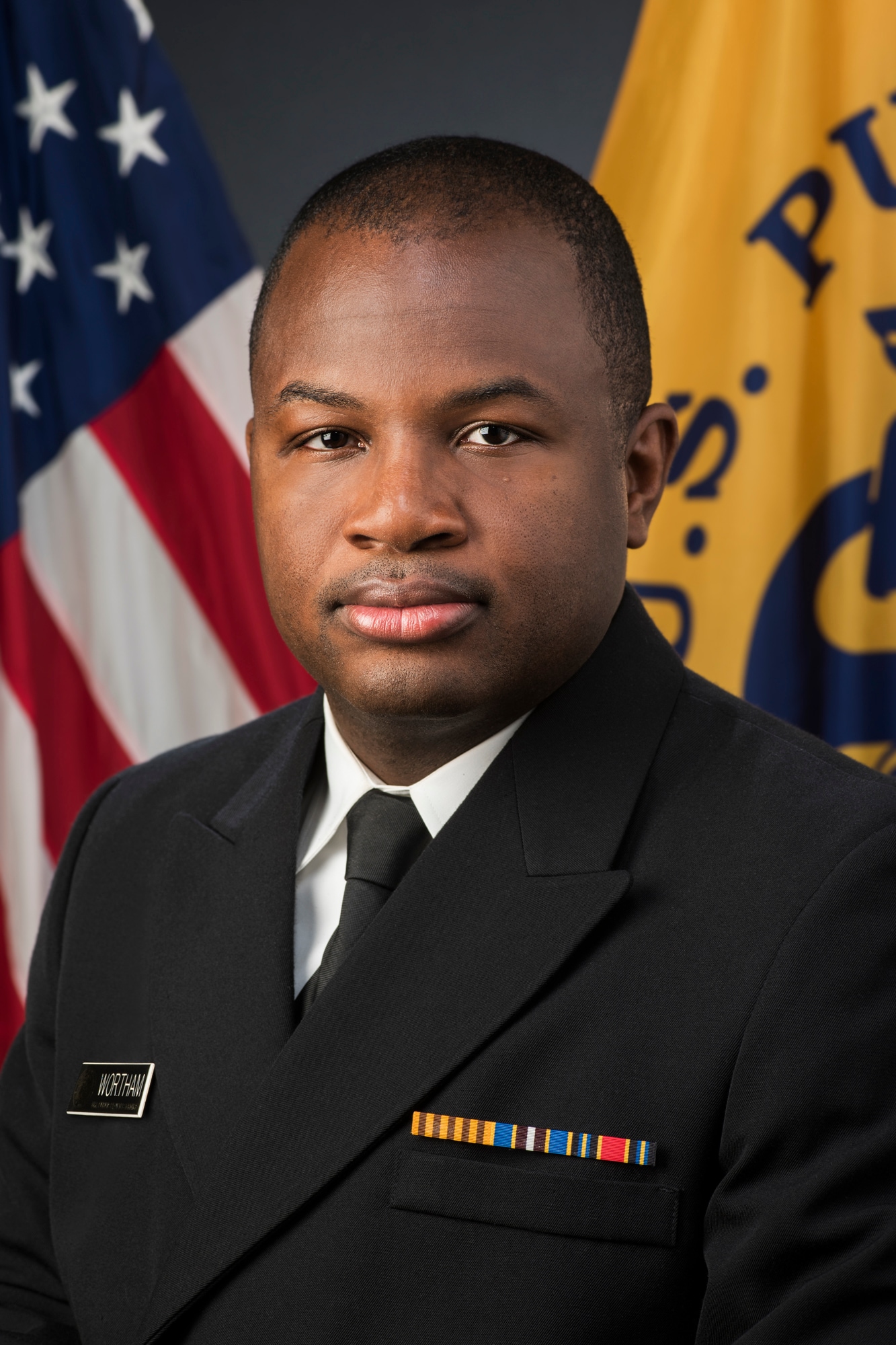 Headshot of Dr. Jonathan. He is in military uniform with the U.S. and U.S. Public Health flags in the background