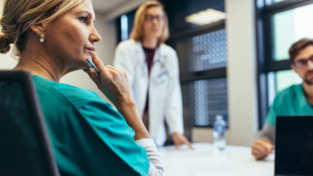 A health care provider listens to colleagues in a meeting