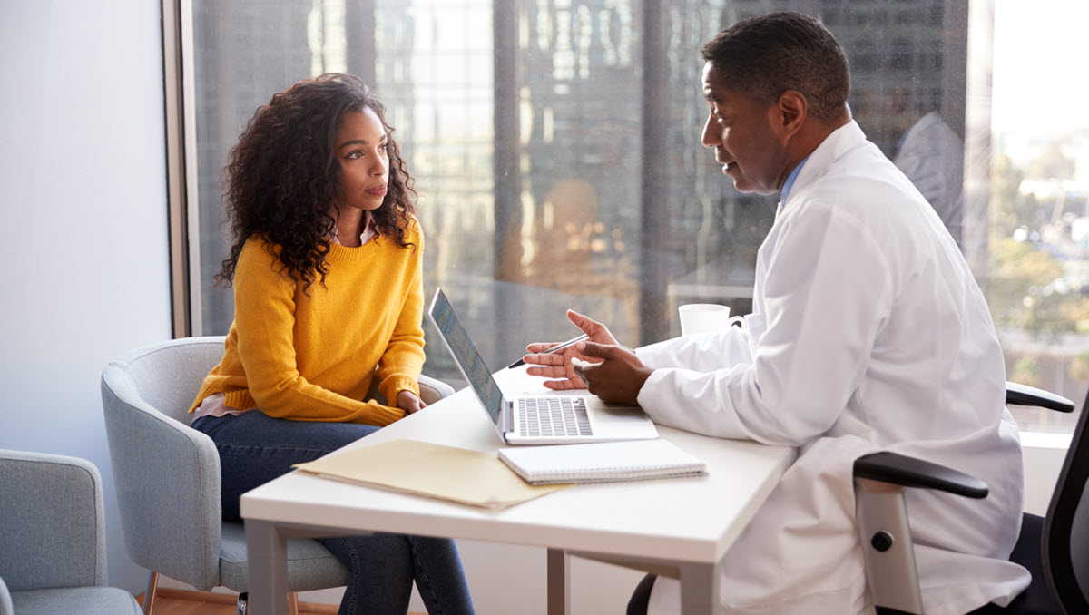 A woman is consulting with a male health care provider in a medical office.