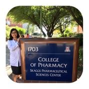 Thu, a tuberculosis survivor, next to the sign for her College of Pharmacy program