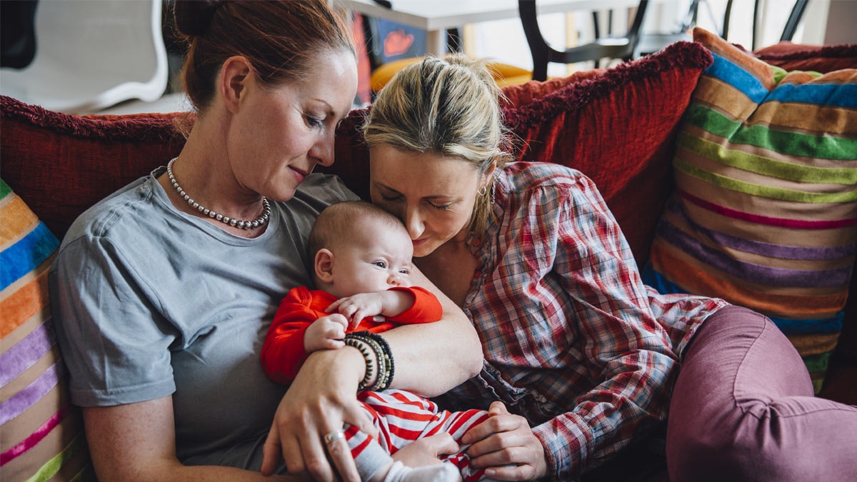 Lesbian couple sitting on couch with infant