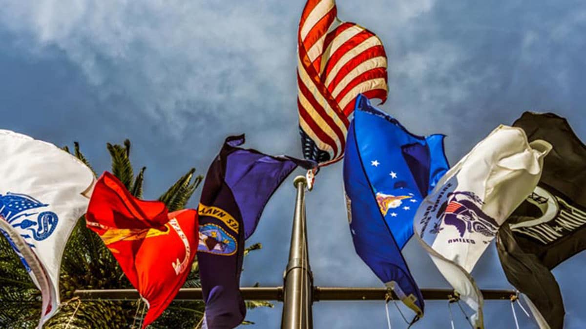United States flag surrounded by U.S. military-related flags.