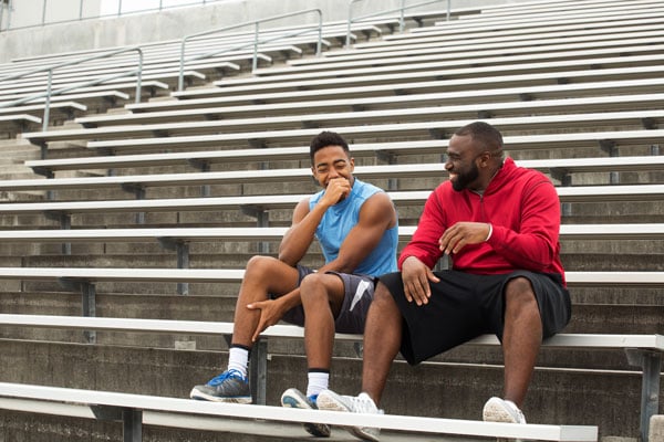 An adult and a student sitting on bleachers