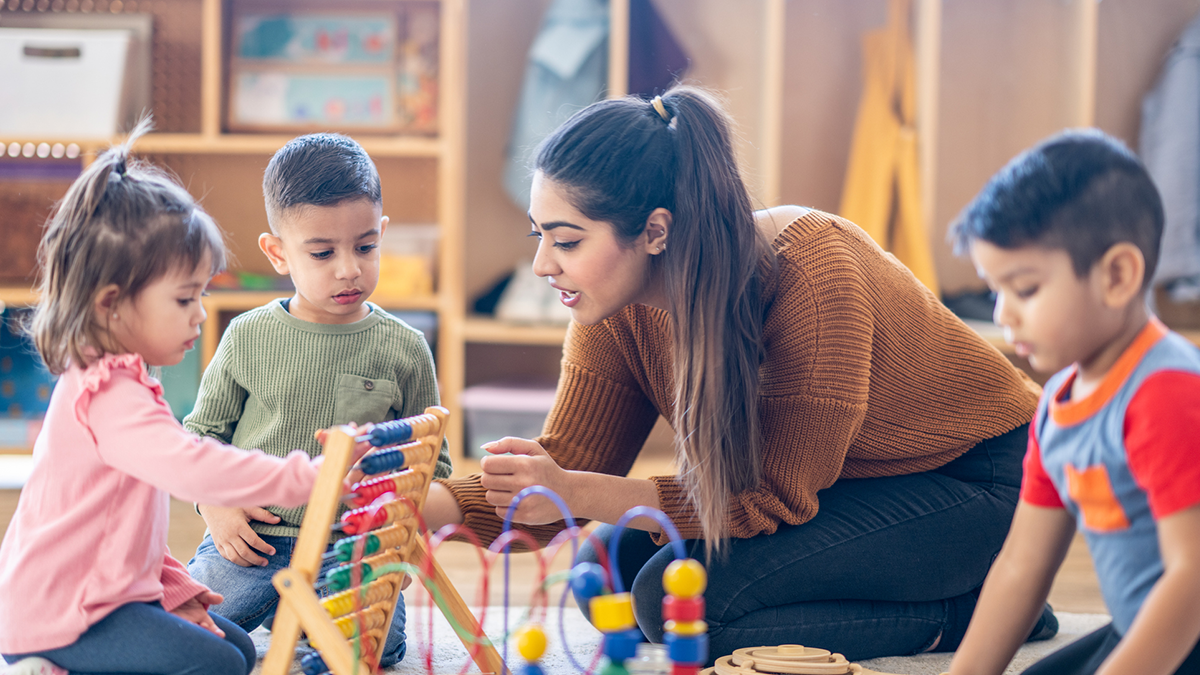 A teacher interacts with young students during play time.