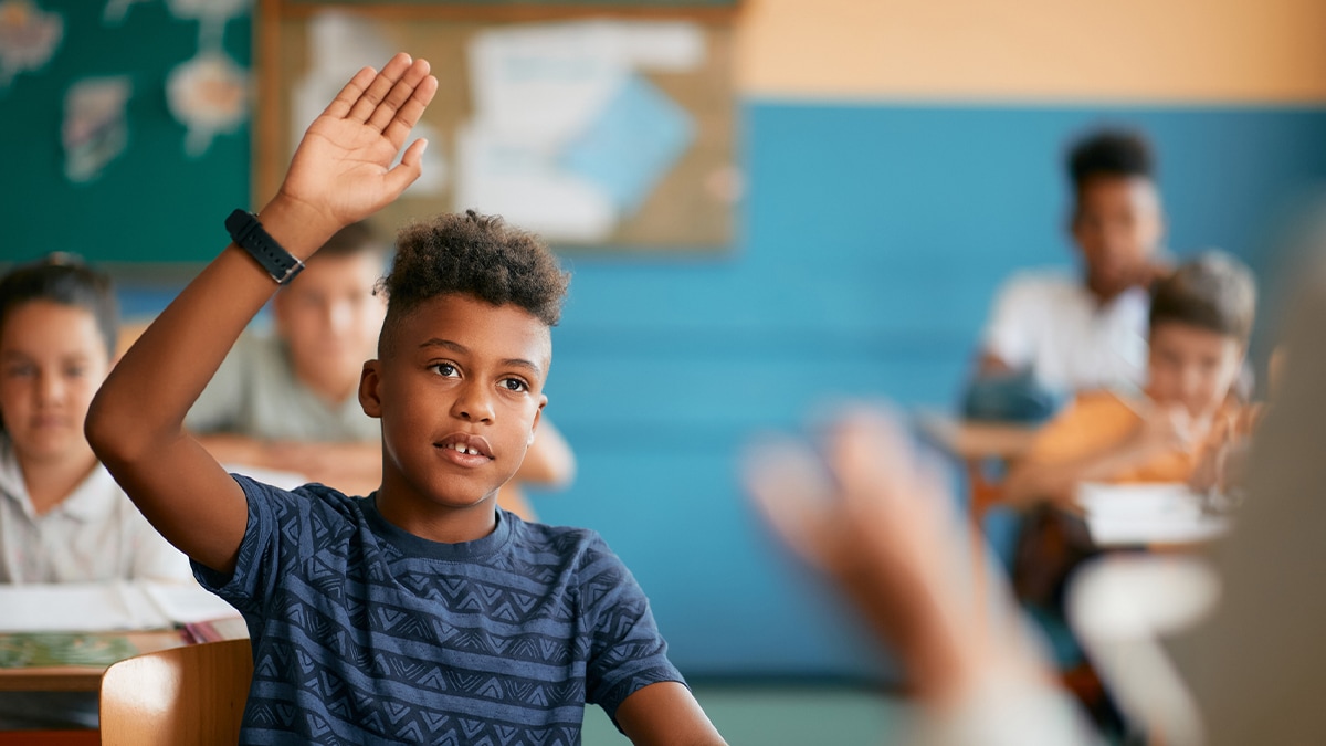 young boy raising his hand in a classroom