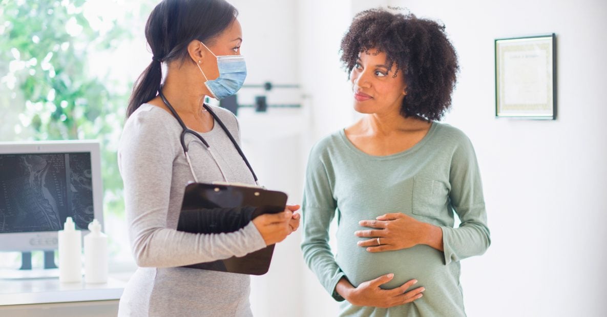 Doctor speaking to pregnant person in healthcare setting
