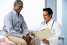male-patient-doctor Male patient sitting next to a male doctor with medical chart