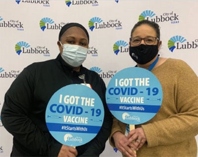 Two masked woman holding up 'I got the COVID-19 vaccine' signs