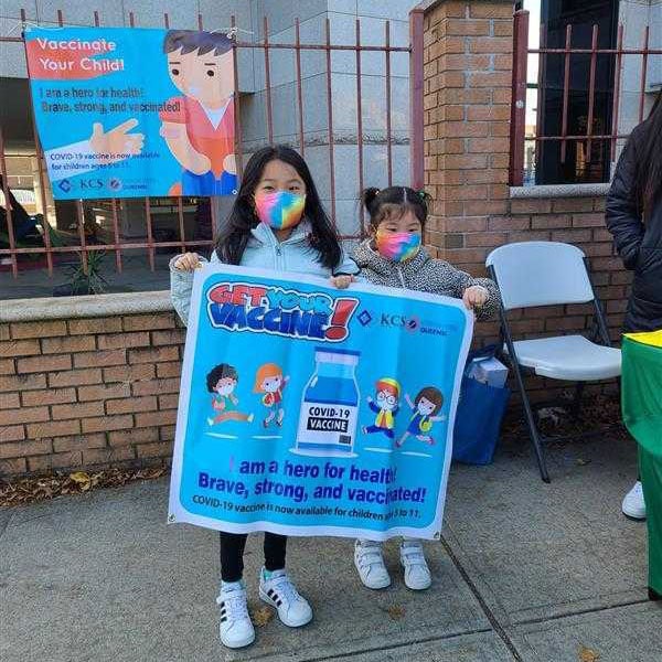 Children holding a 'Get Your Vaccine!' sign