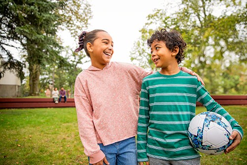 Girl and boy holding a soccer ball playing outside