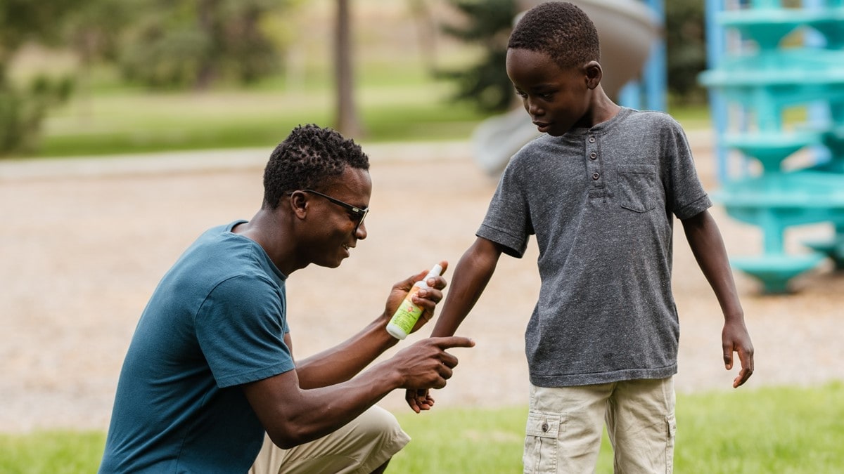 An adult applying insect repellent to a child
