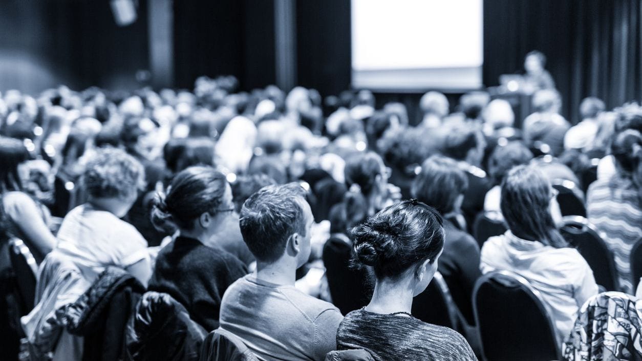 Large room with people watching a presentation.