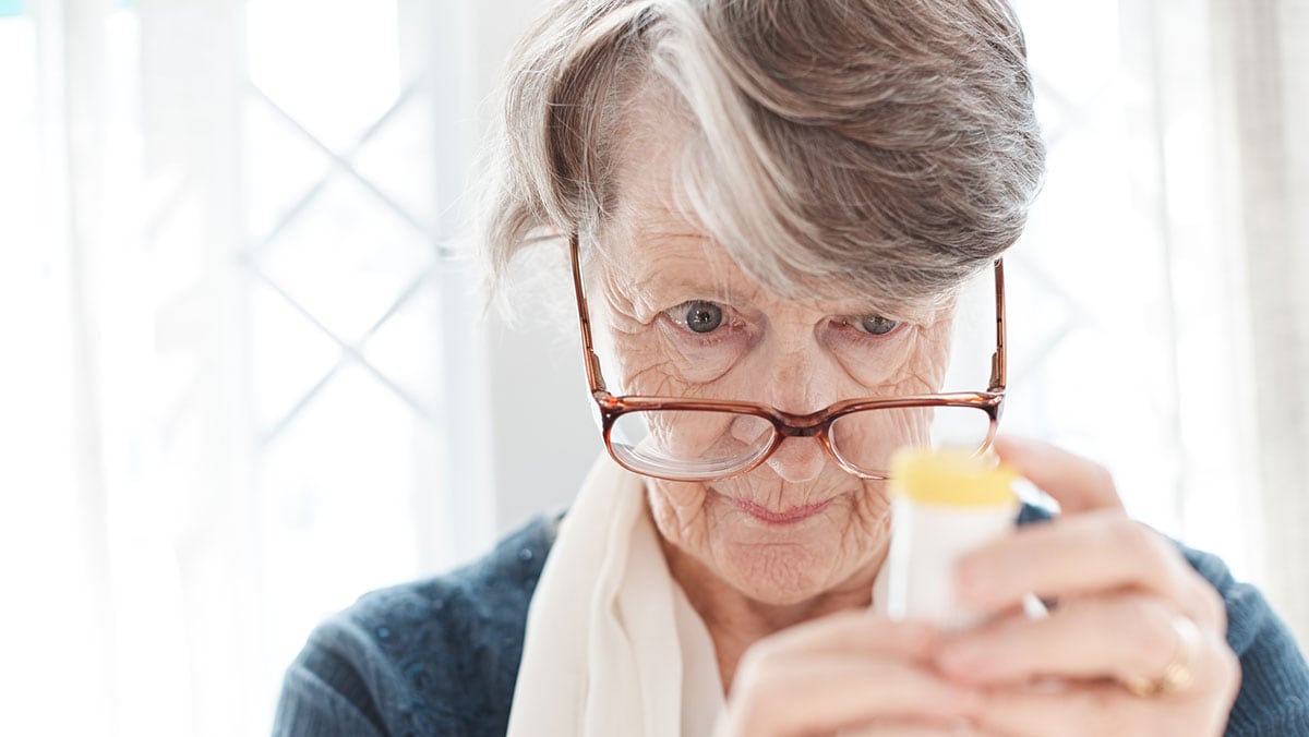 Elderly woman looking at medicine bottle