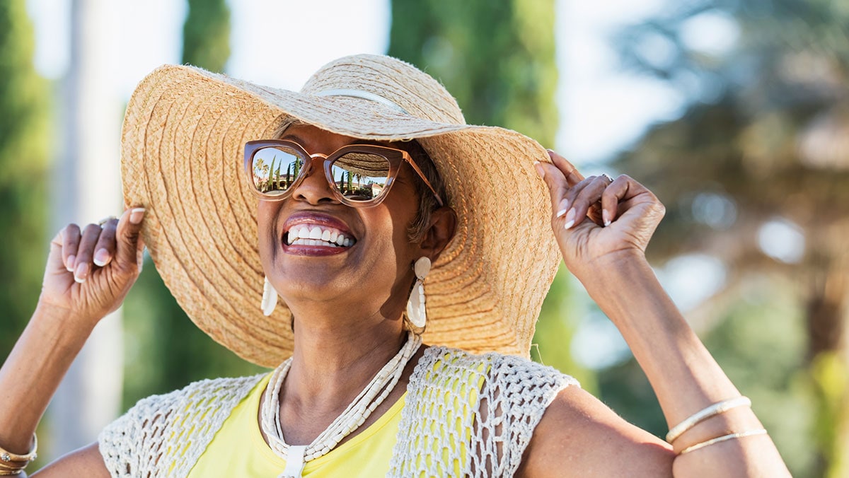Smiling lady with hat and sunglasses outside