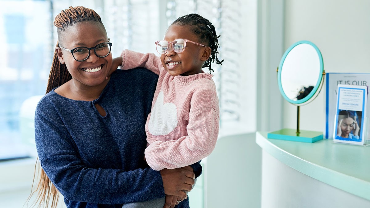 Woman holding little girl wearing glasses