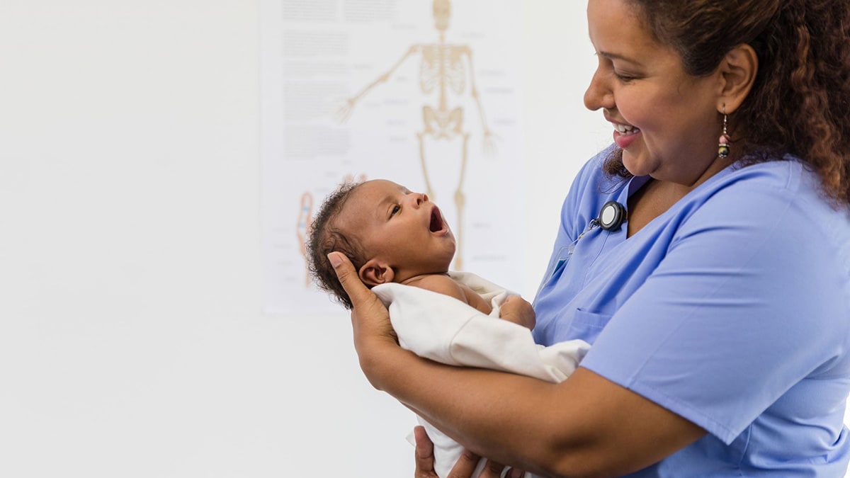 Una enfermera sonríe al contemplar a un recién nacido