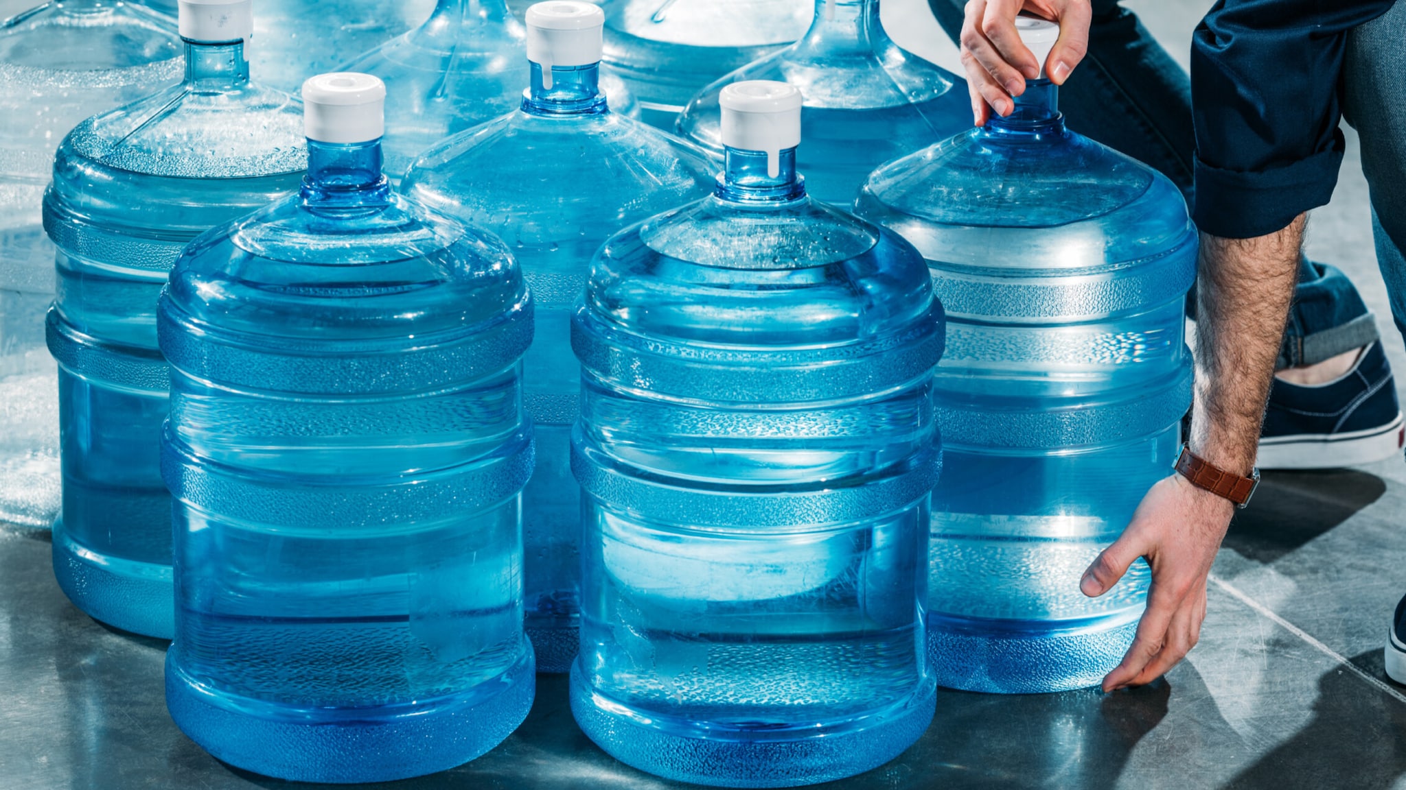 Foto de una persona entregando garrafones transparentes con agua para beber.