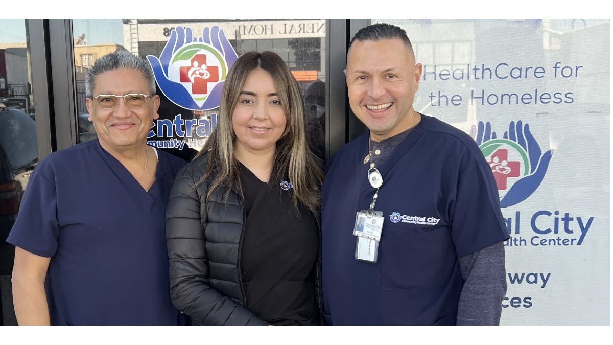 3 Outreach Team workers at Central City smiling and wearing scrubs outside of a health clinic