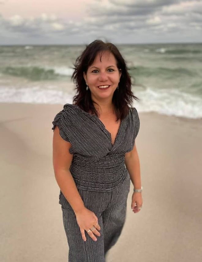 Myrna Leiper smiling at the beach, wearing a gray dress