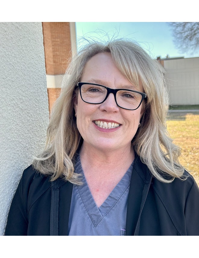 Teresa Plummer smiling wearing scrubs and a blue jacket