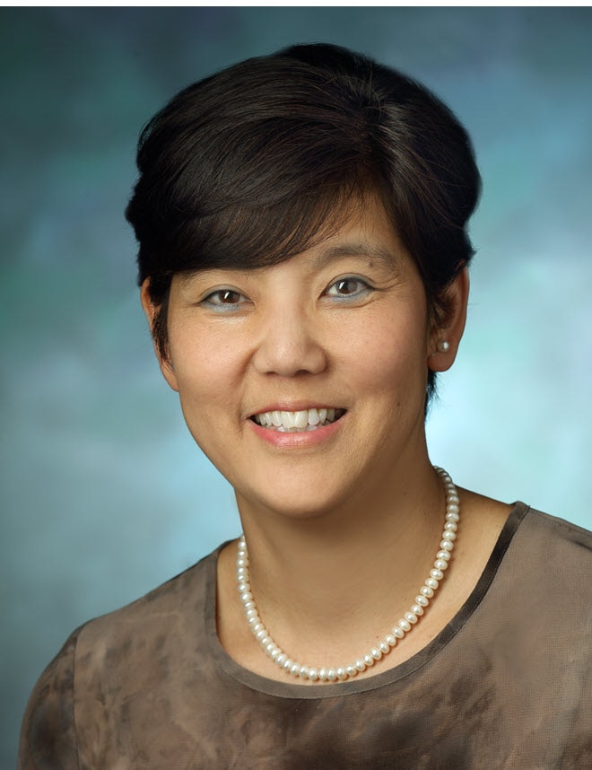 Yukari Manabe smiling wearing a gray shirt and a white necklace