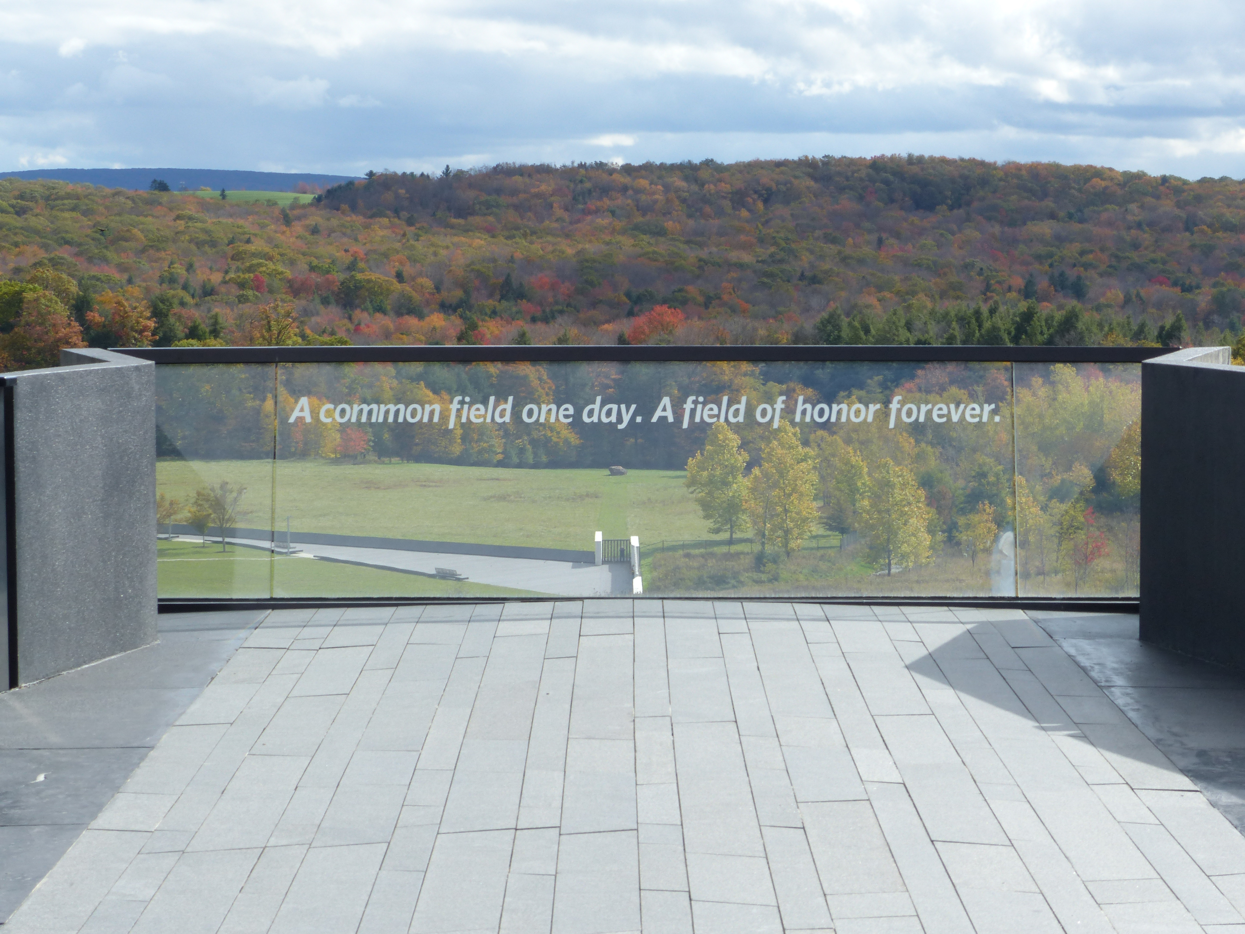 A view of the Flight 93 Memorial’s flight path overlook, featuring a glass barrier inscribed with the quote “a common field one day. A field of honor forever.” The scene pays tribute and stands as a lasting symbol of honor and remembrance.