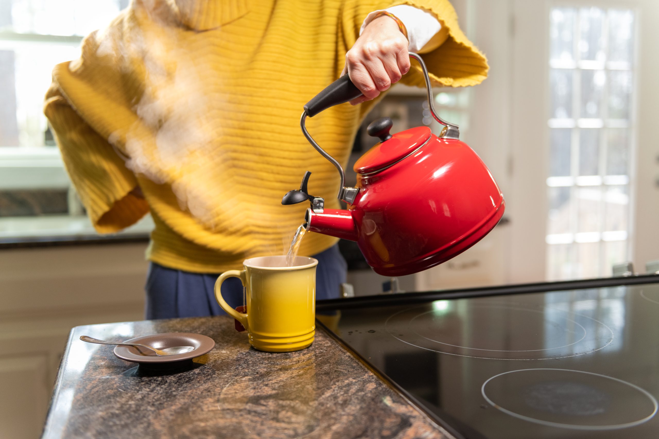 Traveler pours boiled water from a kettle into a mug.