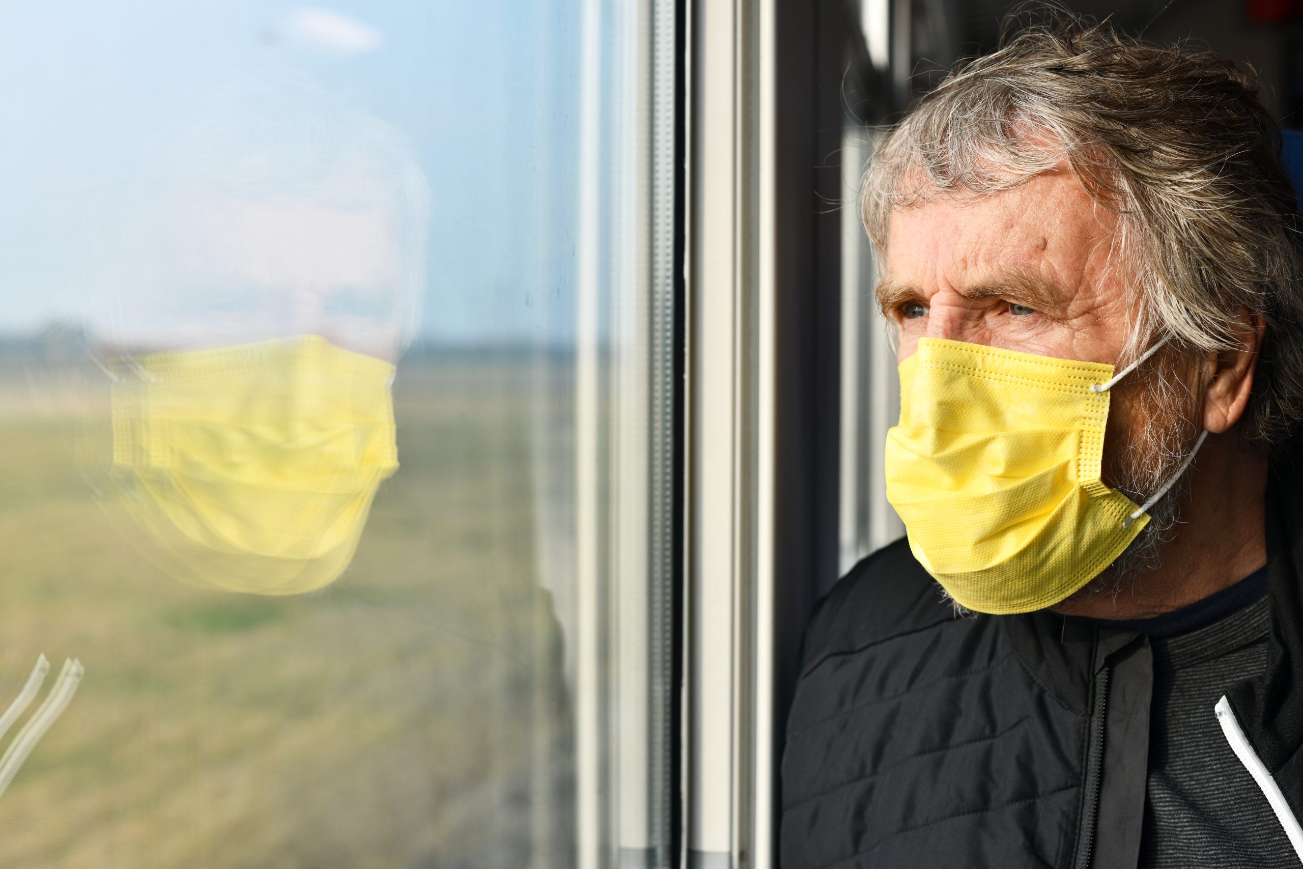 Traveler looking out a window with a mask on.